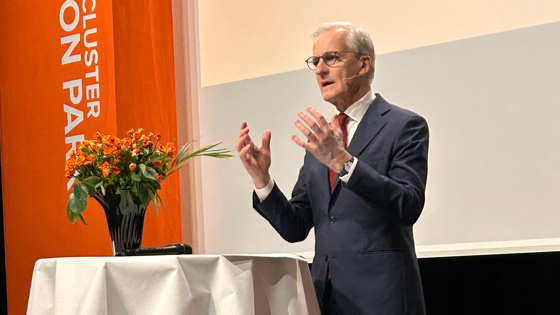 Statsministeren står bak en talerstol på en scene.