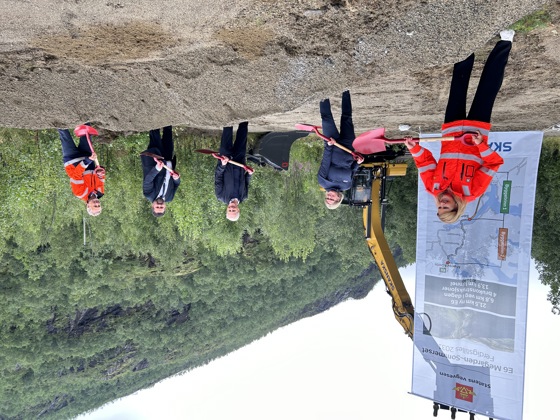 Statsministeren og flere andre står med hver sin spade, og kaster sand.