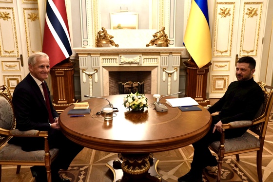 Støre sitter rundt et bord sammen med Zelenskyj.