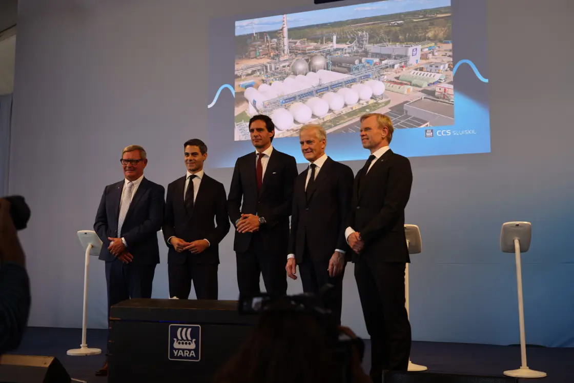 Gruppefoto foran bilde av anlegget i Sluiskil