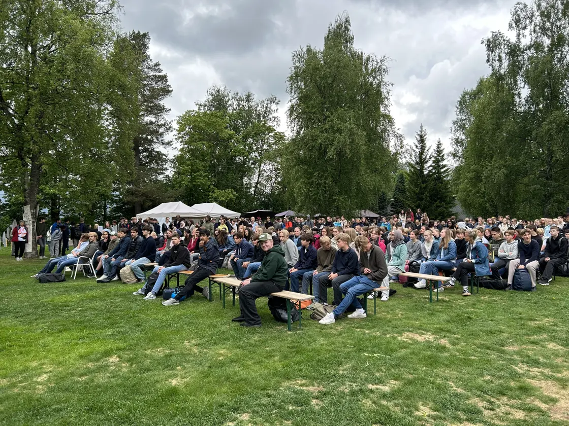 Ungdommer sitter på benker på en grønn plen.