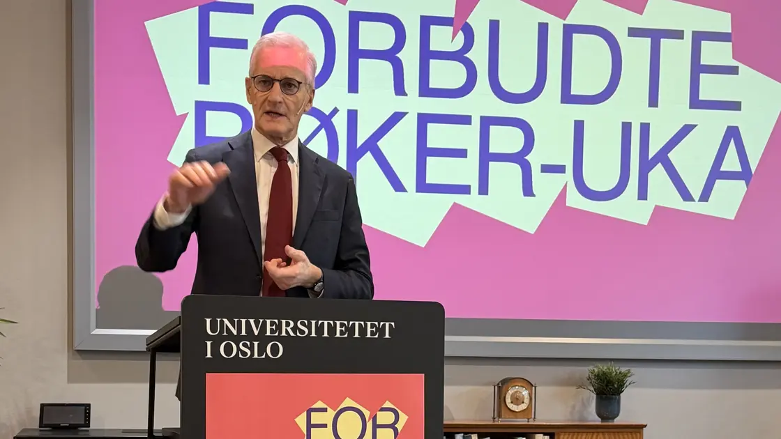 Støre gestikulerer med hendende. Står bak en talerstol.