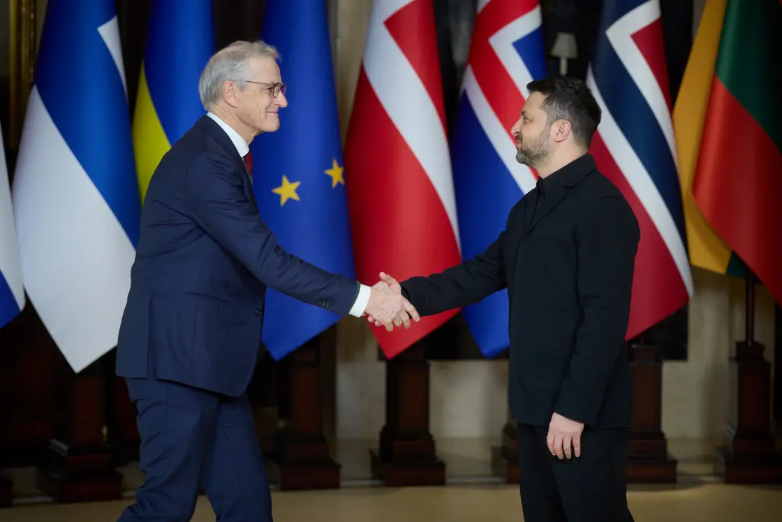 Støre and Zelenskyy greet each other in front of the flags.