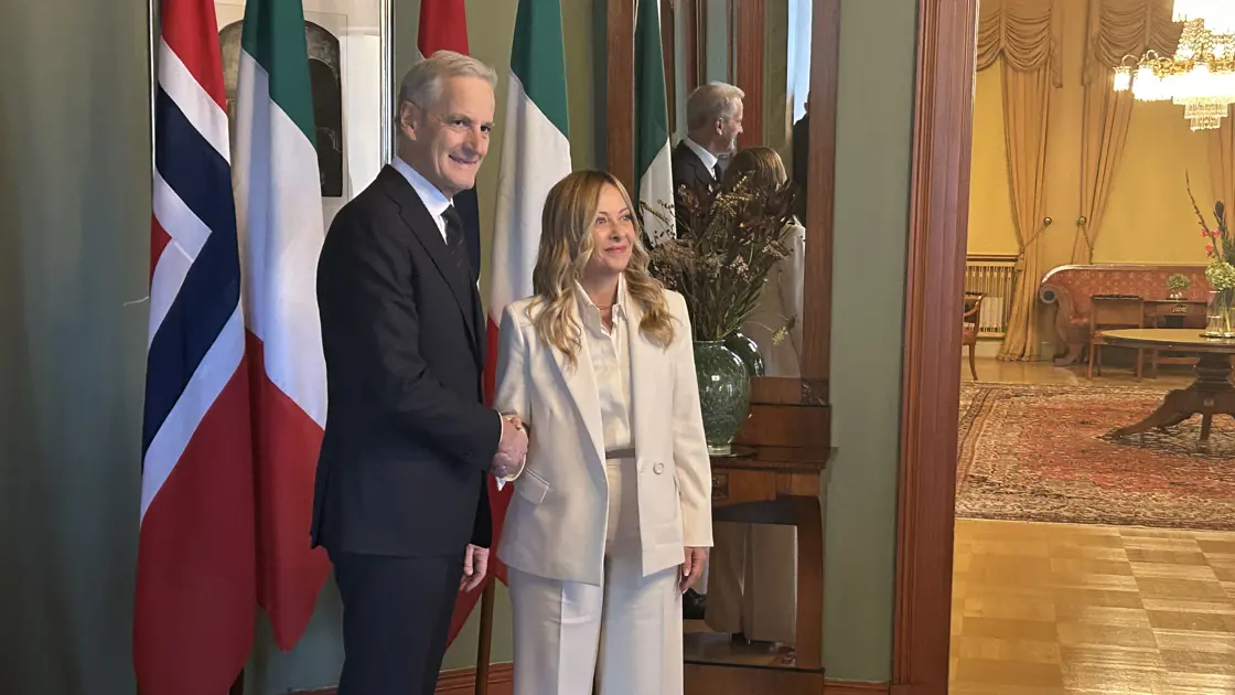 Statsminister Støre tar imot statsminister Meloni foran Italias og Norges flagg.