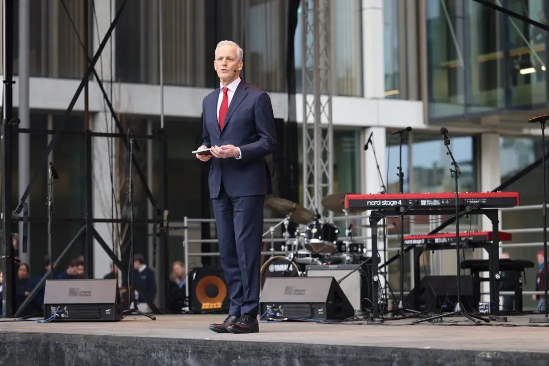 Statsministeren står på scenen, holder talekortene sine i hånden.