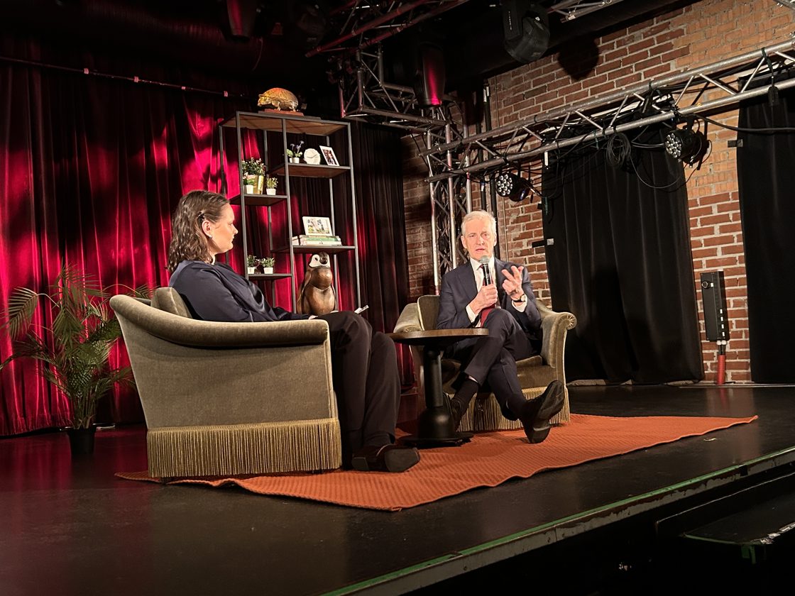 Støre sitter i en stol på scenen i Studentersamunnet i Bergen sammen med en samtalepartner.