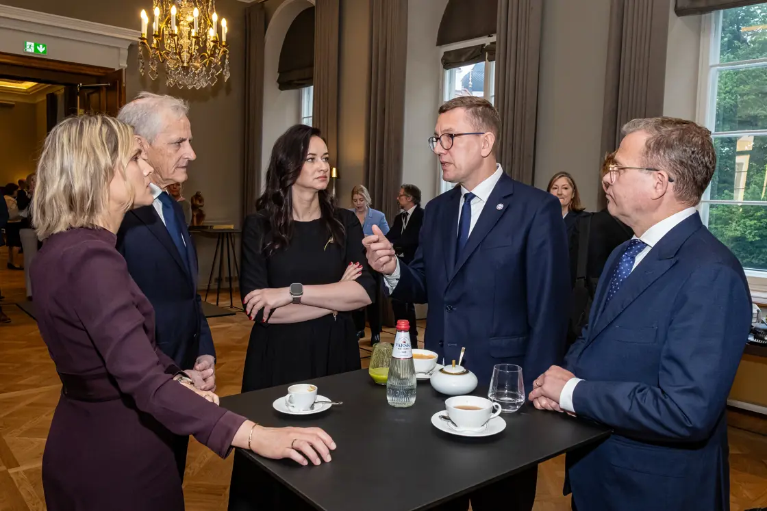 Statsministeren står i en gruppe statsministre rundt et rundt bord.
