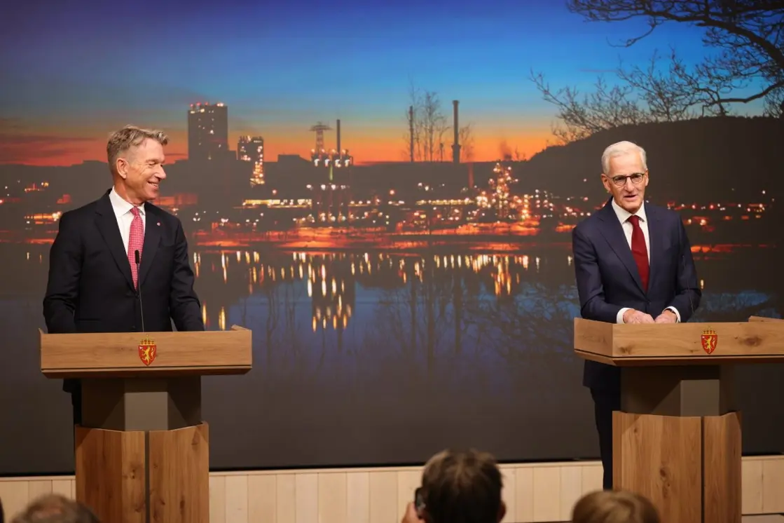 Støre og Aasland står på scenen foran en bakgrunn med bilde fra Herøya i Porsgrunn.