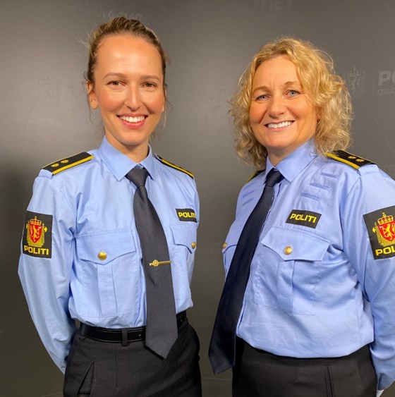 To politi i uniform smiler mot kamera.
