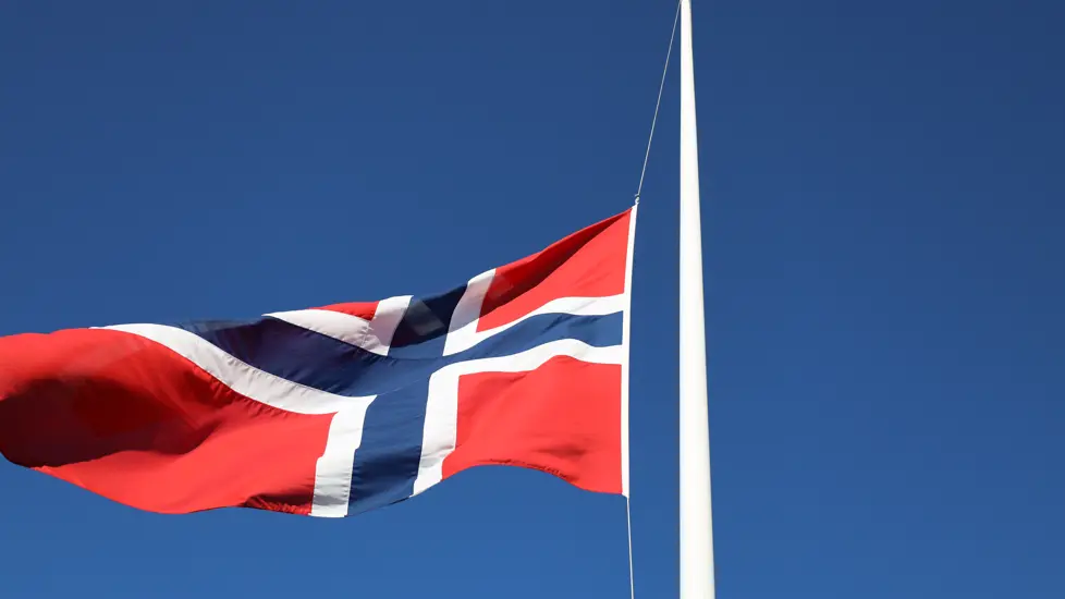 Bilde av flagg på halv stang med blå himmel bak