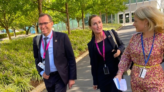 Bilde av klima- og miljøminister Barth Eide gående sammen med to rådgivere på en ganbgvei med park i bakgrunnen