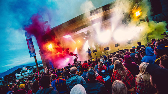 Bilde av scene med røyk, lys og publikum foran