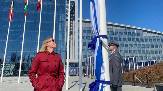Bilde av utenriksminister Anniken Huitfeldt som ser på det finske flagget før det heises i Brussel
