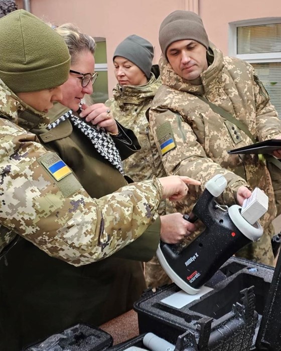 Bilde av ambassadøren som ser på noe av utstyret. To soldater forklarer. 