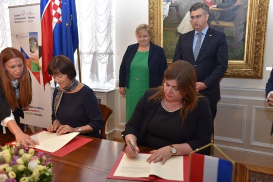 Statsminister Erna Solberg ser på mens de nye samarbeidsavtalene undertegnes.