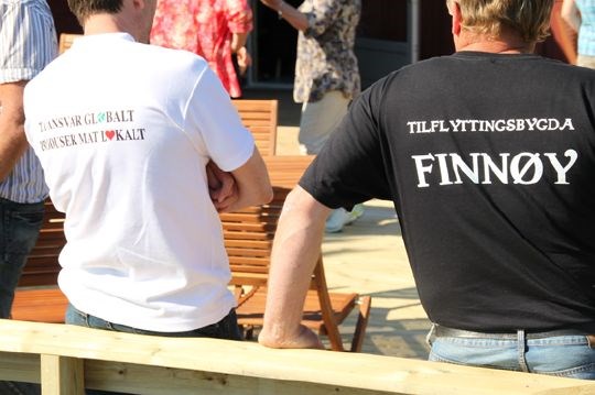 To rygger viser t-skjorte med tekstene: Tilflyttingsøya Finnøy og Ta ansvar globalt - produser mat lokalt 