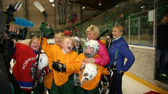 Finansminister Siv Jensen og kulturminister Thorhild Widvey saman med ishockeybarn i Manglerud Ishall. 