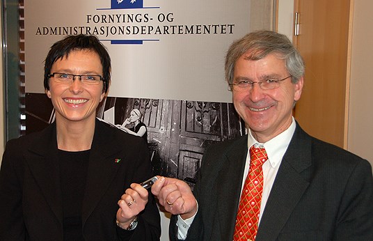 Bilde: Standardiseringsrådets leder Olaf Østensen overleverer forslaget til statsråd Heidi Grande Røys på en minnepinnne. Foto: FAD