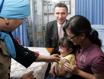 Statsminister Jens Stoltenberg på besøke på helsestajonen Puskemas i Tebetområde i Jakarta. Statsministeren følger med når lille Gladys (20 mnd) i armene på sin mor, Elfan (30), får sin meslingvaksine av helsesøster (tv). Foto: Bjørn Sigurdsøn / SCANPIX