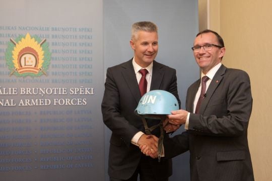 Forsvarsministrene Espen Barth Eide og Artis Pabriks med en hjelm